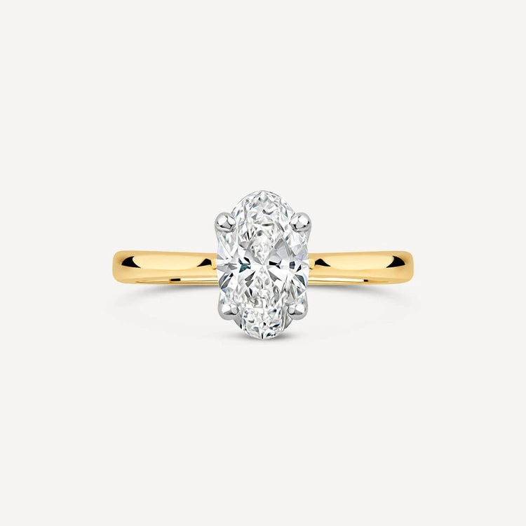 Oval-cut diamond solitaire ring set in a white gold head with a polished yellow gold band.